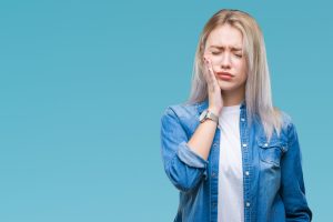 Young blonde woman over isolated background touching mouth with hand with painful expression because of toothache or dental illness on teeth. Dentist concept.